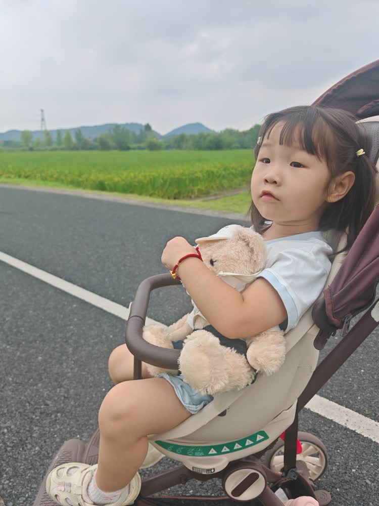小雨坐在推车里抱着小熊